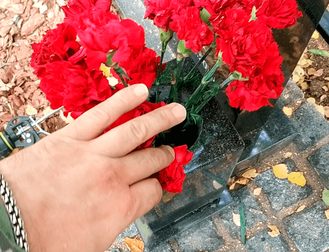Размещение живых цветов в квадратной вазе на могиле
